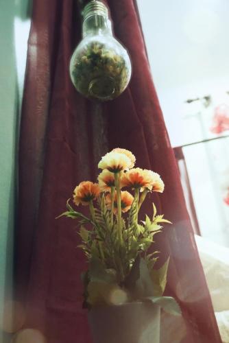 a vase with flowers sitting under a light bulb at The Floral Home in Melaka