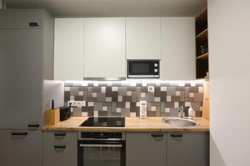 a kitchen with a sink and a microwave at Comfy 2 Room Apartment - Free Parking - 350Mbps WiFi - Netflix in Kaunas