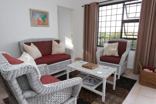 uma sala de estar com cadeiras de vime e uma mesa em Beach Break B&B - Solar Powered em Port Alfred