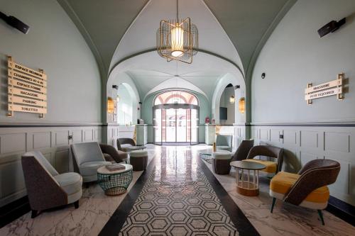 a lobby with chairs and tables and a chandelier at Grand Hôtel Bristol in Colmar