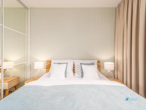 コウォブジェクにあるLazar Apartamenty Nadmorskie Tarasyの大きな白いベッドと2つのランプのある寝室