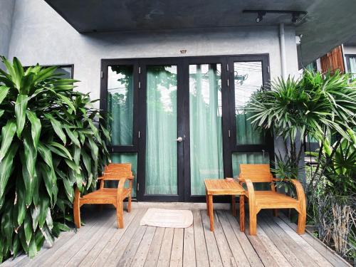 two chairs and a table on a wooden porch at Lamphu House Chiang Mai in Chiang Mai