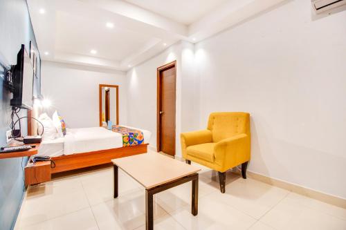 a bedroom with a bed and a chair and a desk at FabHotel The Sun Suites - Yelahanka in Yelahanka