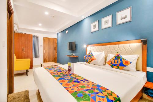 a bedroom with a large bed and a blue wall at FabHotel The Sun Suites - Yelahanka in Yelahanka