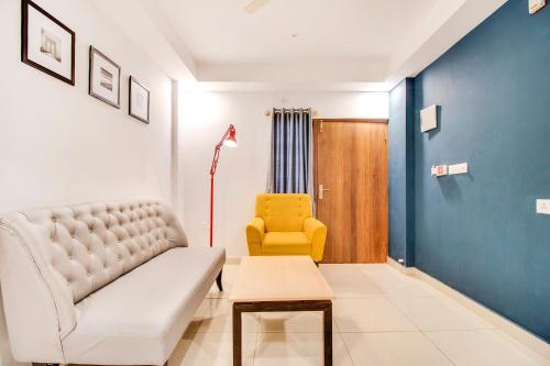 - un salon avec un canapé et un fauteuil jaune dans l'établissement FabHotel The Sun Suites Vinayaka Nagar, à Yelahanka