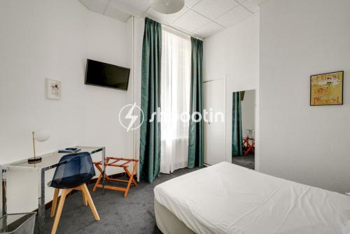 a hotel room with a bed and a desk and a chair at Hotel d'Angleterre in Avignon