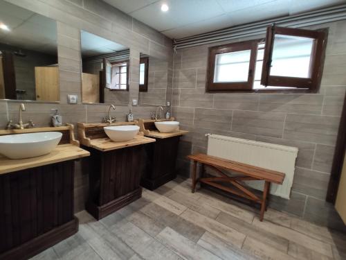 a bathroom with three sinks and a bench at Alberg Les Daines in Espot