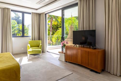 a living room with a flat screen tv and a chair at Fazenda Viegas in Lagos