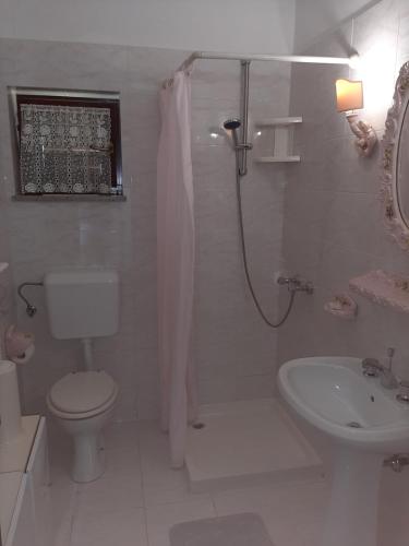 La salle de bains blanche est pourvue de toilettes et d'un lavabo. dans l'établissement House H-ELIOS, à Lovran