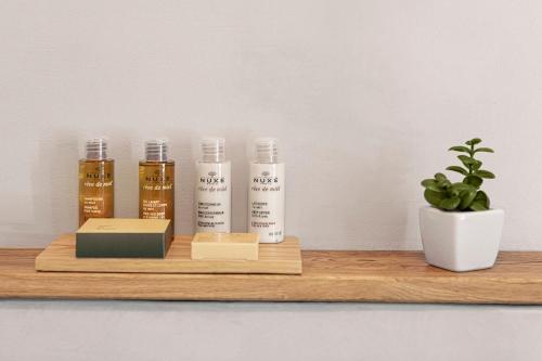a shelf with three bottles of essential oils and a plant at DOMA u nás Boutique hotel & spa in Poprad