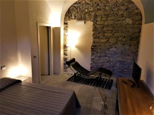 a bedroom with a chair and a stone wall at Villa Ottocento in Campertogno