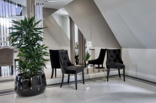 a lobby with black chairs and a potted plant at Hotel & Spa Biały Dom in Gliwice