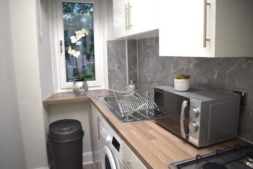 cocina con fregadero y microondas en Kelpies Serviced Apartments- Victoria en Falkirk