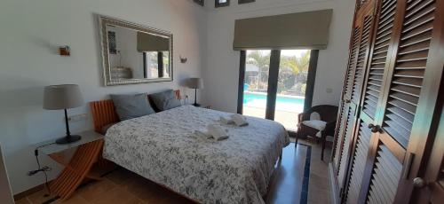 ein Schlafzimmer mit einem Bett, einem Spiegel und einem Pool in der Unterkunft Villa Adais in Playa Blanca
