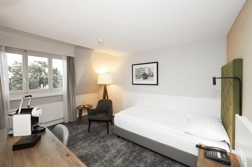 Habitación de hotel con cama, escritorio y silla en Hotel Löwen am See en Zug