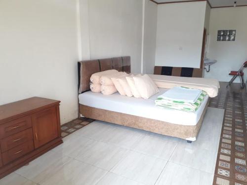 a bedroom with a bed with white pillows and a dresser at Pesona Wisata Alam Ciparay Endah in Bogor