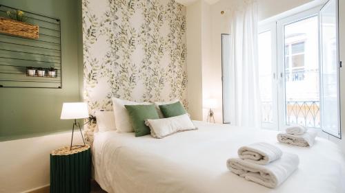 1 dormitorio con 1 cama blanca grande y toallas. en Lineros - Apartments with shared Rooftop en Sevilla