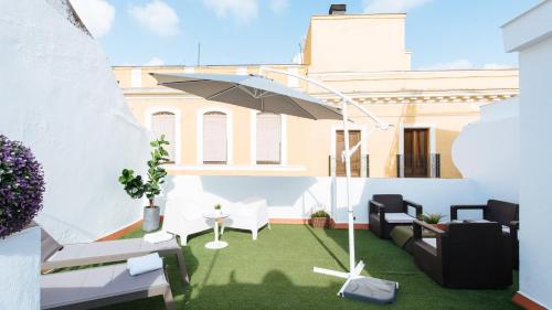 un patio con sombrilla y césped en Lineros - Apartments with shared Rooftop en Sevilla