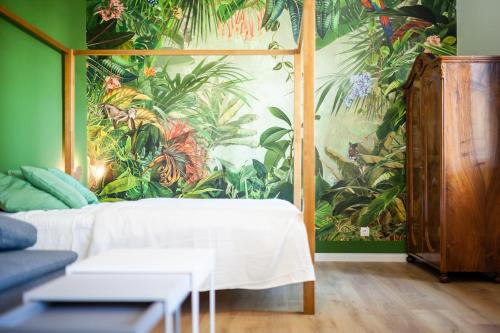 a bedroom with a mural of plants on the wall at ZACHÁR Apartman in Sopron
