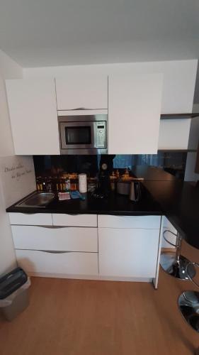 a kitchen with white cabinets and a microwave at Appartements am Schillergarten in Dresden