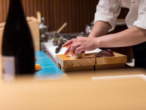 a chef chopping up food on a cutting board at Garden Terrace Fukuoka in Fukuoka