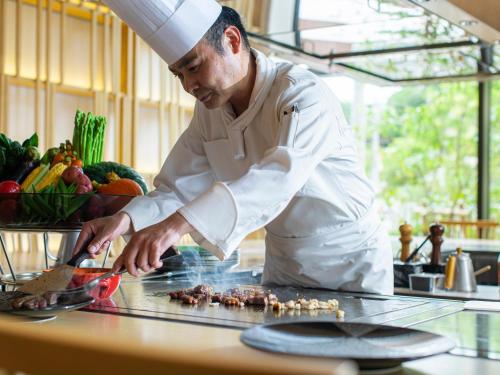 a chef preparing food on a counter in a kitchen at Garden Terrace Fukuoka in Fukuoka