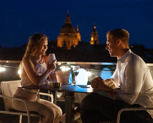 a man and a woman sitting at a table at night at Cortile Hotel - Adults Only in Budapest