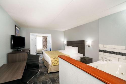 a hotel room with a bed and a bath tub at Baymont by Wyndham Gallatin in Gallatin