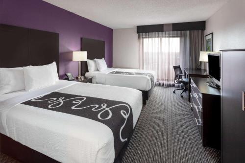 a hotel room with two beds and a desk at La Quinta by Wyndham Minneapolis Bloomington W in Bloomington