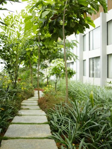 a garden path with trees and plants in front of a building at Hyatt Hyderabad Gachibowli in Hyderabad