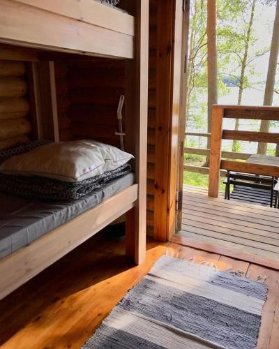 a bed in a wooden cabin with a porch at Koskenselkä Camping in Puumala