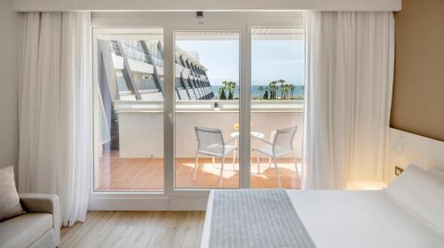 a bedroom with a bed and a balcony with a table and chairs at Ilunion Islantilla in Islantilla