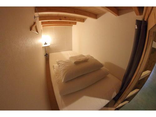 a small room with a bed with towels on it at Travelers' house ROOTs in Takaoka