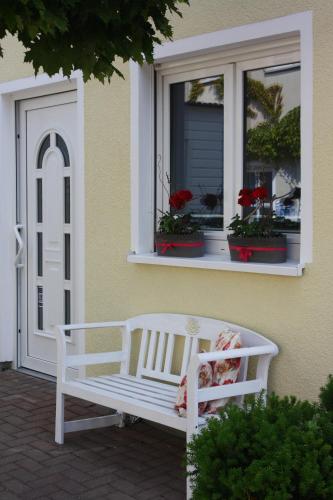 a white bench sitting in front of a window at Ferienhaus Godewind in Kühlungsborn