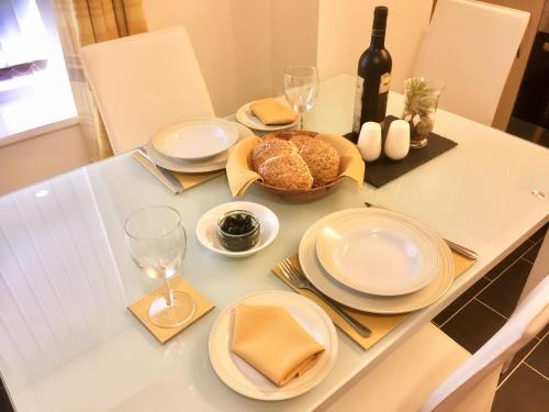 卡納芬的住宿－Chapel St Apartments，一张带盘子和玻璃杯的桌子和一瓶葡萄酒