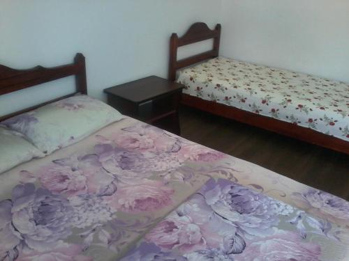 2 Betten in einem Zimmer mit rosa Blumen drauf in der Unterkunft Complex Turistic Ocna Sibiului in Ocna Sibiului