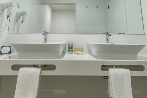 
a white sink sitting under a mirror in a bathroom at MH Atlantico in Peniche
