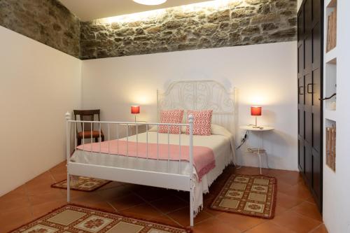 a bedroom with a white bed with pink pillows at Casa do Vale 2 in Peso da Régua