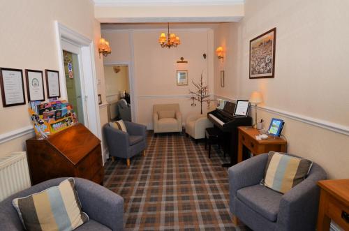 een woonkamer met stoelen en een piano bij St. Hilary Guest House in Llandudno