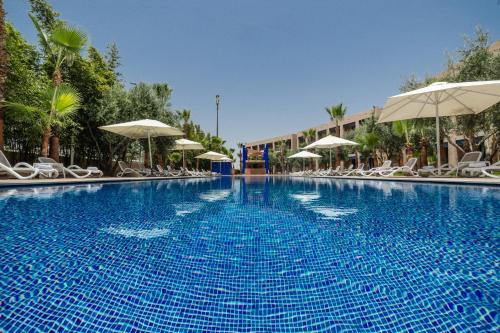 a large blue swimming pool with chairs and umbrellas at Wazo Hotel in Marrakech