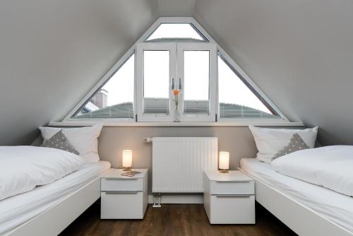 a attic bedroom with two beds and a window at Appartement Lille Kamp 2 in Westerland