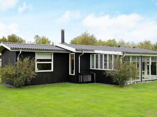 uma casa preta com um relvado verde em frente em 6 person holiday home in Dannemare em Dannemare