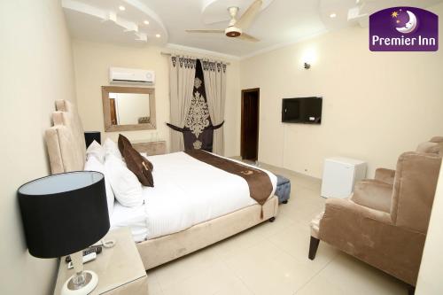 a bedroom with a bed and a tv and a chair at Premier Inn Grand Gulberg Lahore in Lahore