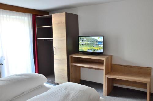 a bedroom with a bed and a television on a shelf at Appartements Kroner in Nauders
