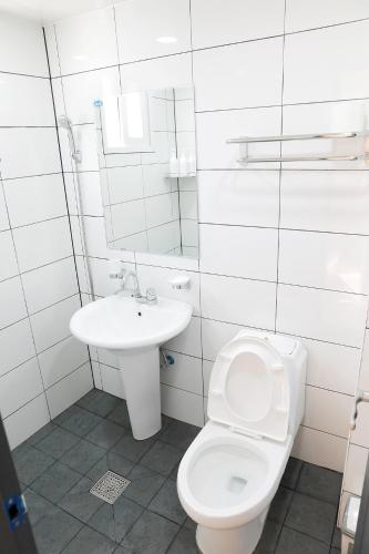 a white bathroom with a toilet and a sink at Minihotel Poongdaengi in Gyeongju