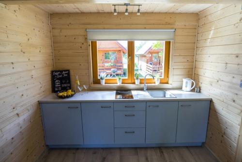 uma cozinha com um lavatório e uma janela em Dadaj Summer Camp - całoroczne domki Rukławki em Biskupiec