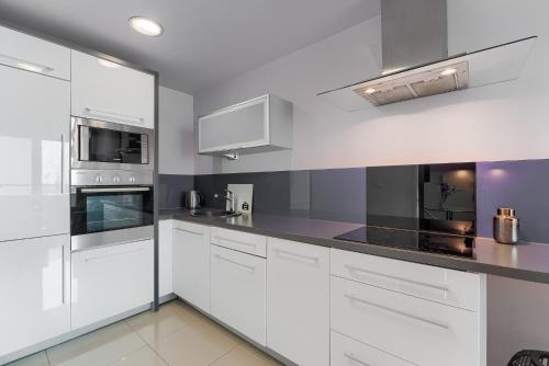 a kitchen with white cabinets and black counter tops at Apartamenty AMB Bandurskiego in Szczecin