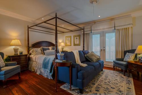 a bedroom with a canopy bed and a blue couch at The Kenwood Inn Oldest Bed and Breakfast, St Augustine Historic District in St. Augustine