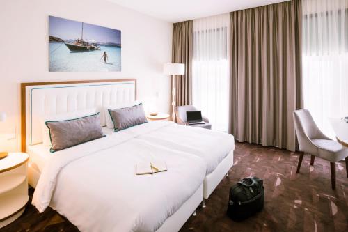 ein Hotelzimmer mit einem großen weißen Bett und einem Schreibtisch in der Unterkunft Mercure Hotel MOA Berlin in Berlin