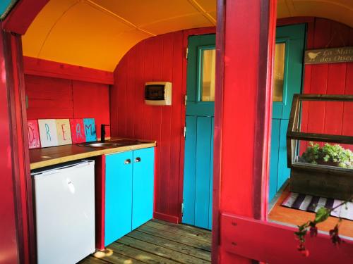 a kitchen with red and blue walls and a counter at La Maison des Oiseaux. Roulotte in Achicourt